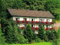 una casa con un balcón con flores rojas. en Pension Waldfrieden, en Oberharmersbach