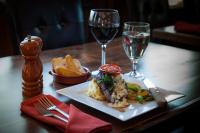 un tavolo con un piatto di cibo e due bicchieri di vino di Summit Mountain Lodge and Steakhouse a East Glacier Park