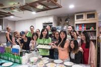 a group of people standing in a kitchen with a tray of food at Hualien Wow Hostel in Hualien City