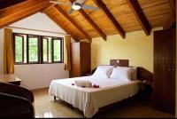 a bedroom with a large bed with a ceiling fan at Villa Sole in Anse Volbert Village