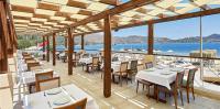 ein Restaurant mit Tischen und Stühlen und Blick auf das Meer in der Unterkunft Fİ Light Solto Boutique Beach Hotel in Selimiye