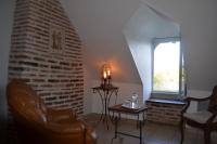 a living room with a chair and a brick wall at LA MAISON DU PECHEUR in Chaumont-sur-Loire