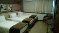 a hotel room with two beds and a chair at Klein Ville São Leopoldo in São Leopoldo