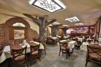 a restaurant with tables and chairs and a tree on the wall at Hotel&SPA Jawor in Zawoja