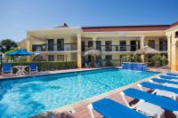 Una piscina frente a un hotel con sillas y sombrillas. en Days Inn by Wyndham Florida City, en Florida City