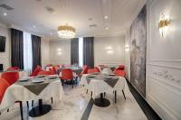 イヴァーノ・フランキーウシクにあるGrand Hotel Roxolanaのテーブルと赤い椅子、シャンデリアのあるレストラン