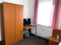 a room with a desk with a television and a cabinet at Hotel Mivano Lehrte in Lehrte