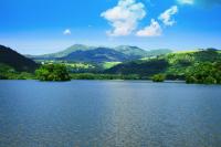 a large lake with trees and mountains in the background at Hôtel Domaine du Lac Chambon in Murol