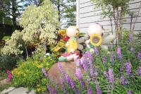 two dolls sitting on a rock in a garden with flowers at Yilan Pine Villa Homestay in Luodong