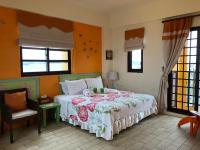 a bedroom with a bed and a chair and windows at Remember Sea View B&amp;B in Huxi