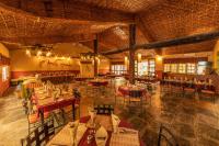 Un restaurante con mesas y sillas en una sala. en Green Mansions Jungle Resort, en Sauraha