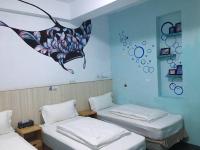 two beds in a room with a butterfly painting on the wall at Light Blue Hostel in Hengchun South Gate