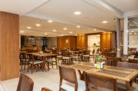 ブルスケにあるTri Hotel Executive Brusqueの木製のテーブルと椅子、テーブルトップが備わるレストラン