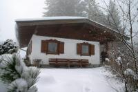 a cabin in the snow with a bench in front at Ferienhaus Soregina in Ellmau