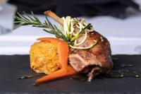 Un trozo de carne con zanahorias en un plato negro. en Astley Bank Hotel, en Darwen