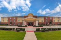 Un gran edificio de ladrillo con un patio delante. en Comfort Suites Ennis, en Ennis