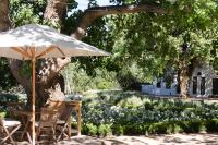 Una mesa y sillas bajo una sombrilla en un jardín. en La Paris Estate, en Franschhoek