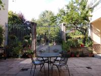 eine Terrasse mit einem Tisch, Stühlen und einem Zaun in der Unterkunft Le Patio Gironnais in Saint-Girons