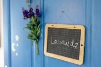 a chalkboard hanging on a blue wall with a vase of flowers at Gîte Chambres d&#39;hôtes Le Bellevue in Montbrun-les-Bains