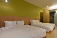 two white beds in a room with green walls at In Young Hotel in Kaohsiung
