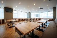 盛岡市にあるドーミーイン盛岡の木製のテーブルと椅子、テレビがあるレストラン