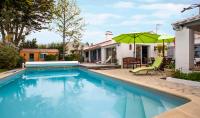 a swimming pool with a green umbrella next to a house at Les Yeux Bleus Bed &amp; Breakfast in Noirmoutier-en-l&#39;lle