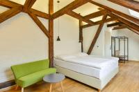 a bedroom with a bed and a green chair at Hotel Garden Court in Prague