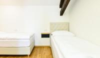 two beds in a room with white walls and wooden floors at Hotel Garden Court in Prague