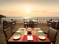 a wooden table with chairs and a view of the ocean at Taj Holiday Village Resort & Spa, Goa in Candolim