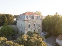un ancien bâtiment en pierre avec un toit rouge dans l&#39;établissement Logis Hôtel Résidence Les Cèdres, à Villeneuve-lès-Avignon