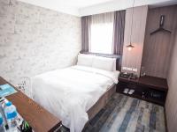 a small bedroom with a bed and a window at Khan Hotel in Kaohsiung
