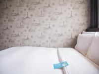 a white bed in a bedroom with a wall at Khan Hotel in Kaohsiung