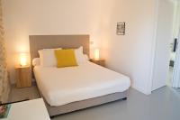 a bedroom with a white bed with a yellow pillow at Hôtel Le 23 in Sauternes