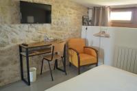a room with a desk and two chairs and a television at Hôtel Le 23 in Sauternes