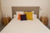 a bedroom with a white bed with colorful pillows at Hôtel Le 23 in Sauternes