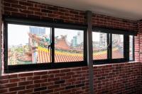 a window in a brick wall with a view of a building at Longshan Inn in Taipei