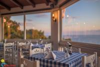 Un restaurante con mesas y sillas con vista al mar. en Bella Vista Apartments, en Pelekas