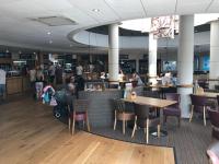een restaurant met tafels en stoelen en mensen die er eten bij Rockley Park - Coral in Poole