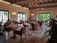 Un restaurante con mesas y sillas de madera y ventanas. en Domaine de Monrecour - Hôtel & Restaurant - Proche de Sarlat, en Saint-Vincent-de-Cosse