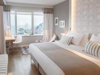 a bedroom with a large bed with a desk and a window at Hotel Bellevue Dubrovnik in Dubrovnik