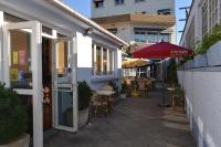 パンタンにあるLe Cheval Noir Hôtel Paris Pantinの空き歩道(テーブル、椅子、傘付)