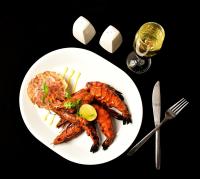 a plate of food with shrimp and rice and a glass of wine at Petit Palais in Puducherry