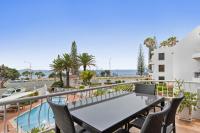 a table and chairs on a balcony with a view of the ocean at Alexandria Apartments in Alexandra Headland