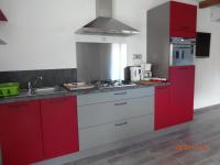 a kitchen with red cabinets and a sink at mini villa studio que du bonheur in Calenzana