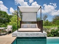a bed with a canopy over a pool at Rosewood Phuket in Patong Beach