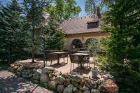 a patio with tables and chairs and a stone wall at Platan Garden Rooms & Restaurant in Hajdúszoboszló