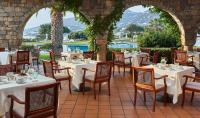 um restaurante com mesas e cadeiras brancas e uma piscina em Elounda Beach Hotel & Villas, a Member of the Leading Hotels of the World em Elounda