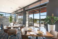 Un restaurante con mesas y sillas y un gran ventanal. en Mercure Kooindah Waters Central Coast, en Wyong