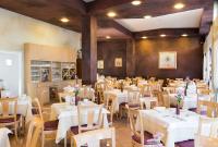 Un comedor con mesas y sillas blancas. en Hotel Meeting, en Stresa