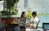 a man and woman sitting at a table in a restaurant at Four Seasons Hotel Hong Kong in Hong Kong